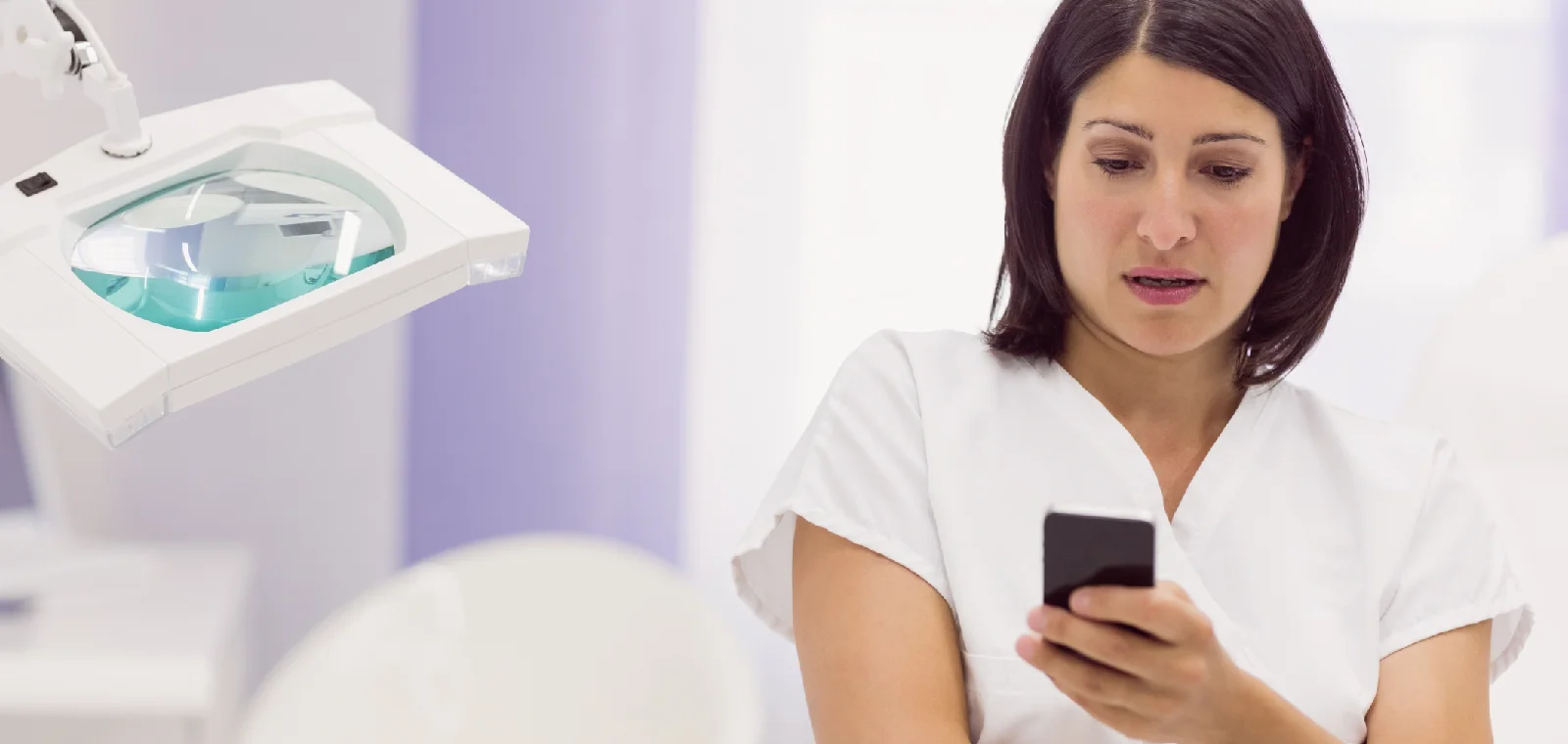 Clinician in a treatment room reading a message on a smartphone