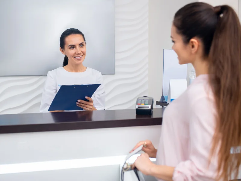 Receptionist greeting a patient at a clinic front desk