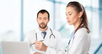 Two clinicians reviewing information together at a laptop