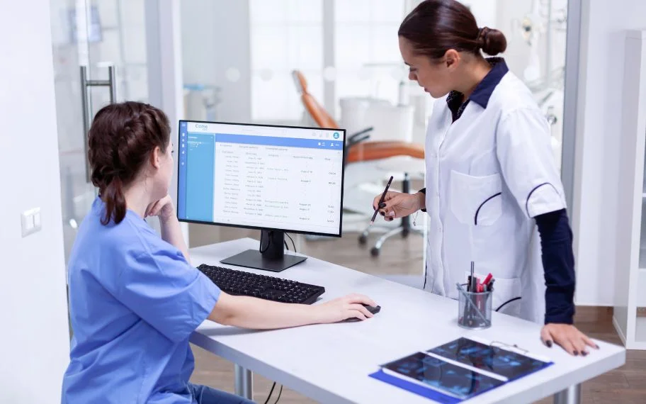 Nurse working at a computer while a colleague reviews files