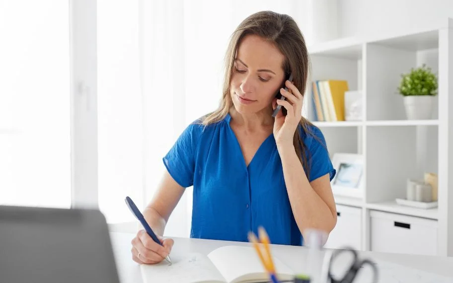 Staff member on a phone call taking notes at a desk